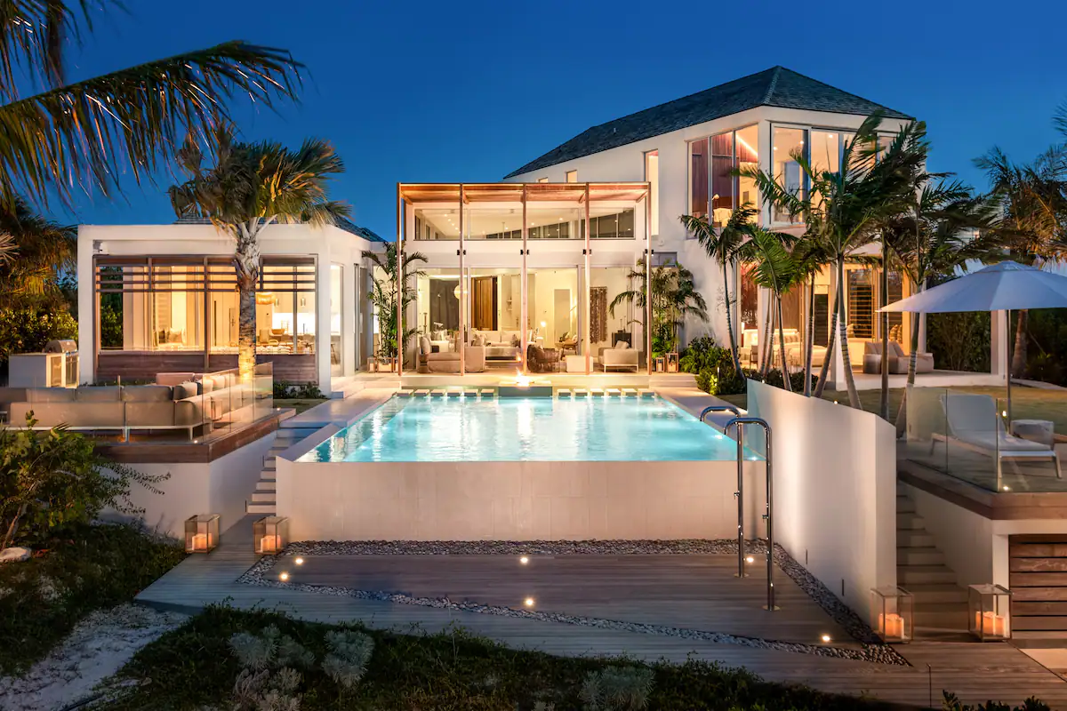 The expansive pool sparkles under the moonlight.