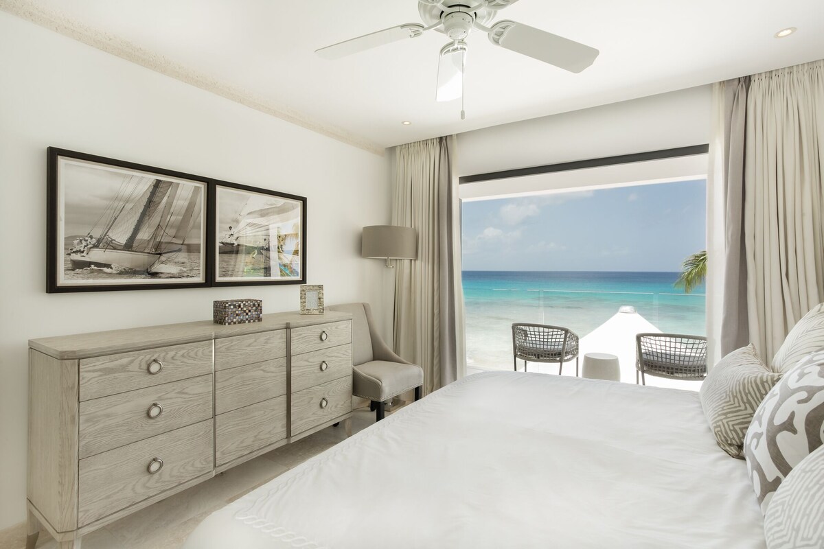 A luxurious master bedroom featuring floor-to-ceiling windows that provide breathtaking panoramic views, a king-sized bed with opulent bedding, and tasteful decorations.